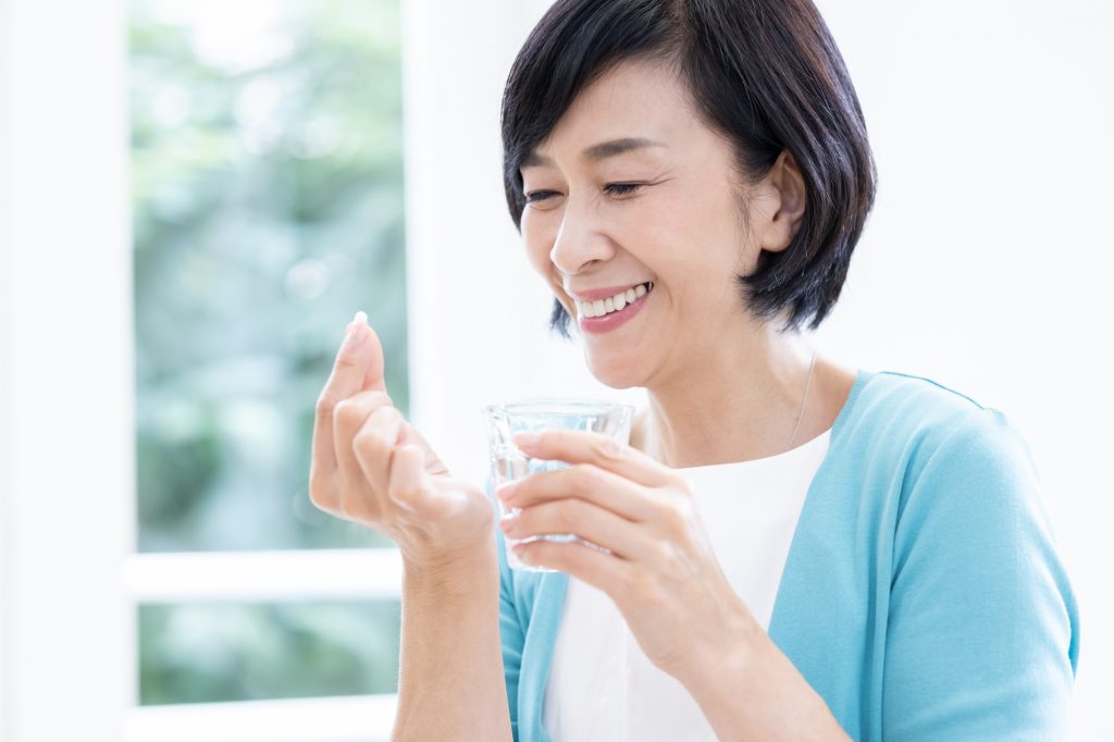 薬を笑顔で飲む女性